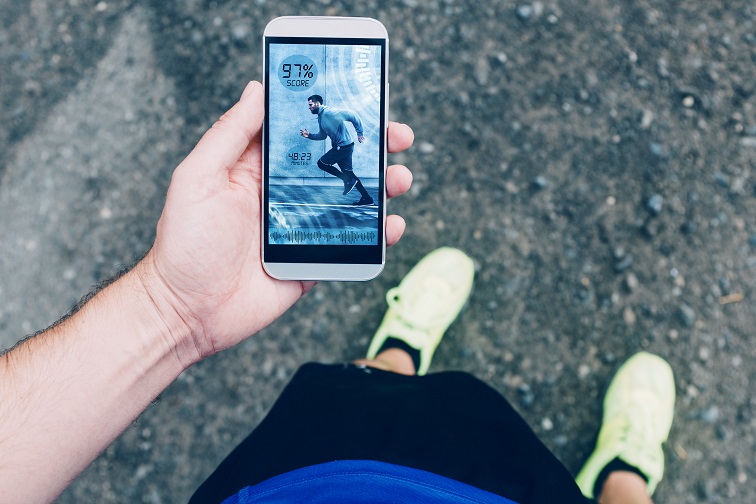Auf dem Bild ist ein Jogger zu sehen, der auf eine Fitness-App schaut.